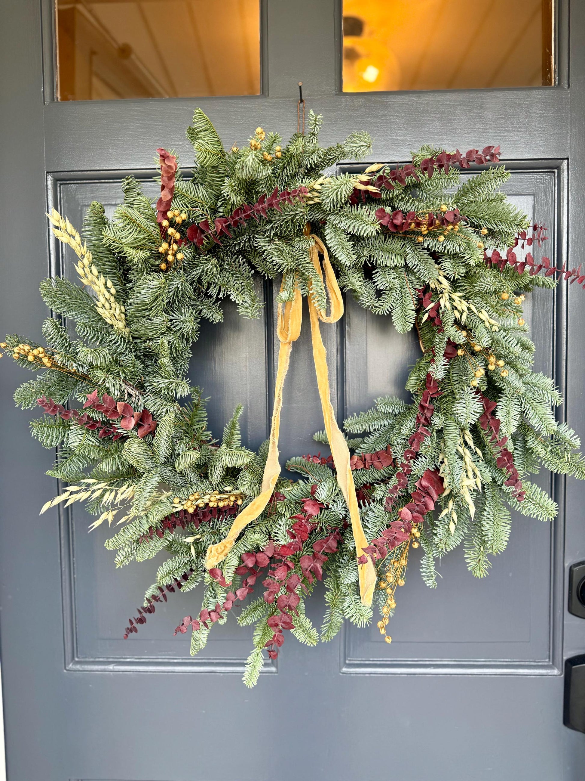 Holiday wreath featuring fresh noble fir, preserved eucalyptus, dried flax and  a gorgeous gold velvet ribbon. 
Adorn a wall, mantel or sheltered door; this fresh, dried and preserved wreath is the perfect way to add beauty to your space.