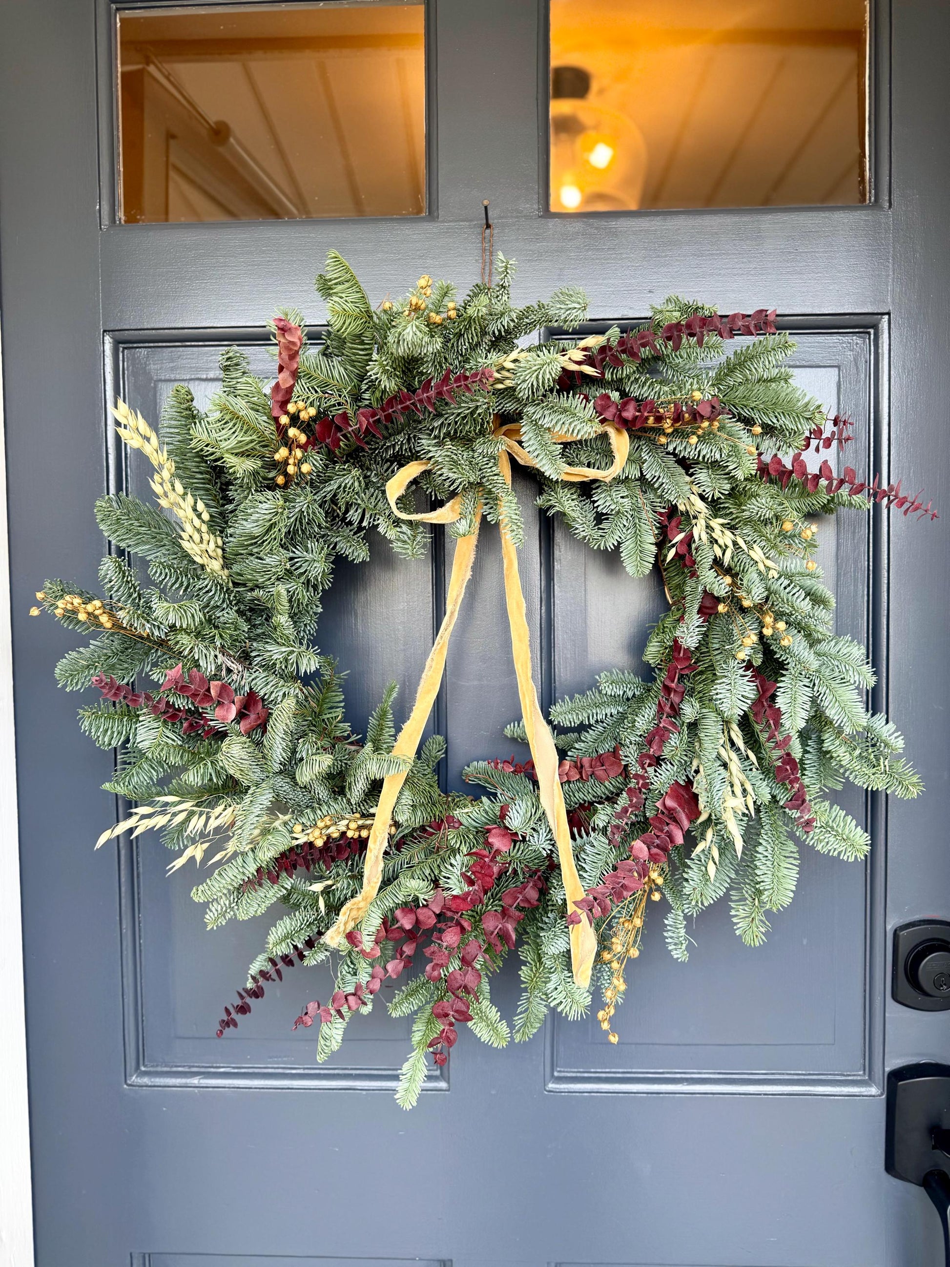 Holiday wreath featuring fresh noble fir, preserved eucalyptus, dried flax and  a gorgeous gold velvet ribbon. 
Adorn a wall, mantel or sheltered door; this fresh, dried and preserved wreath is the perfect way to add beauty to your space.
