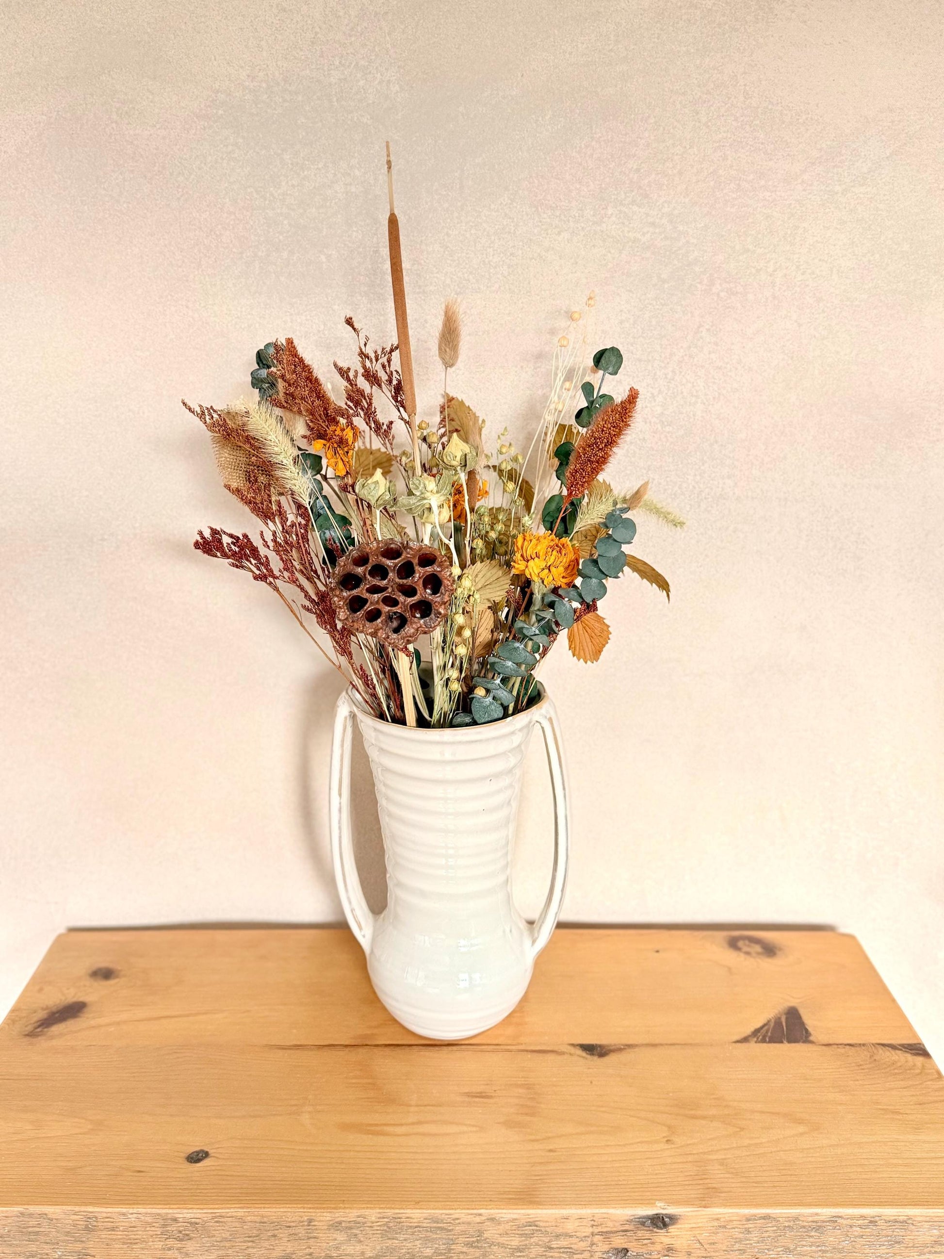 The Blissful bouquet is a stunning Fall inspired bouquet featuring preserved eucalyptus and magnolia, dried marigolds, millet, flax, pods and bunny tails. Stunning as a centerpiece for your Thanksgiving table or all year round for the Fall lovers.