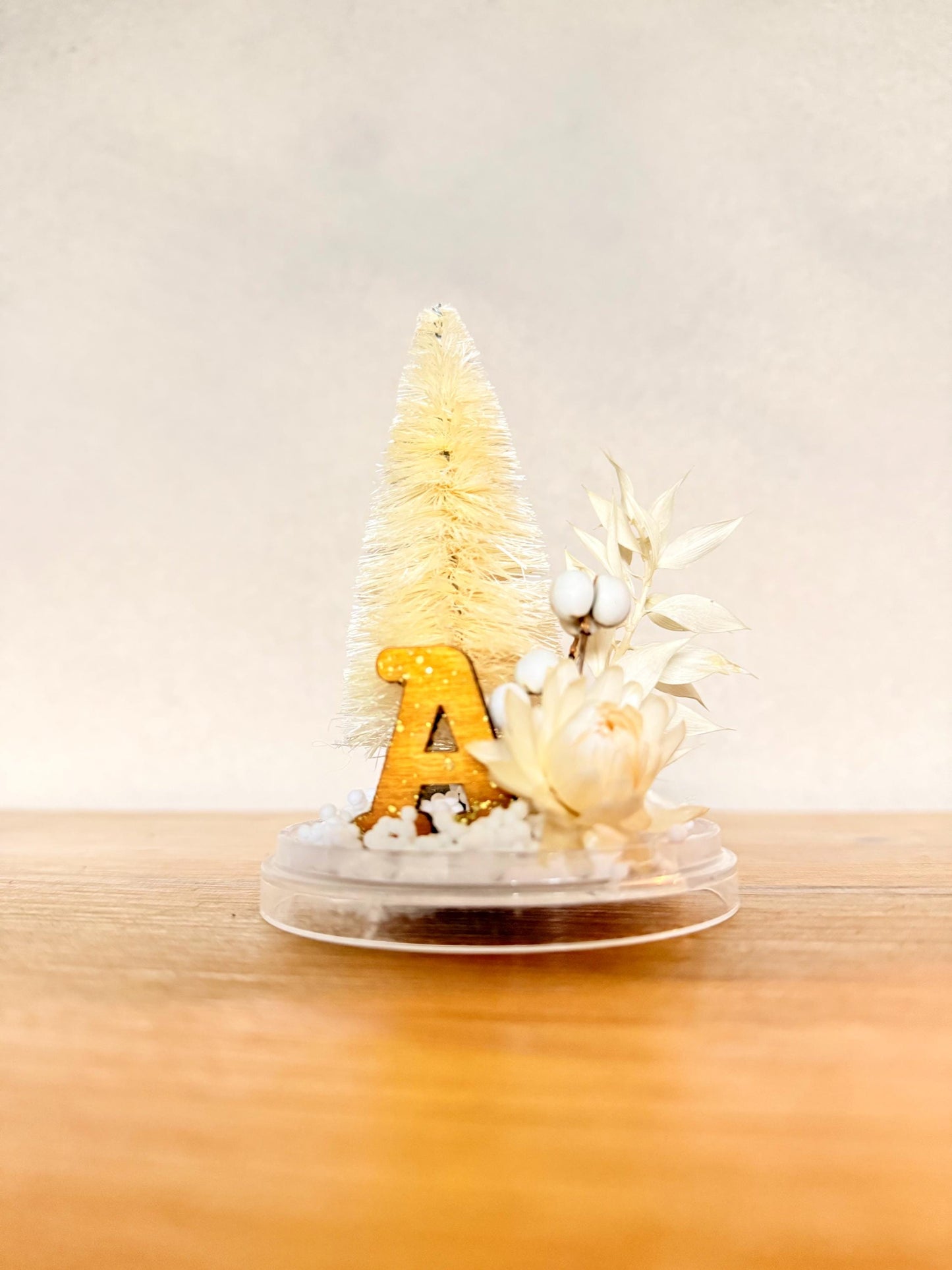 Personalized with initial Ornament - Preserved eucalyptus, dried tallow berries and strawflower, bottlebrush tree and a ochre and sparkle wooden letter on a snow base; hung by a gold color velvet ribbon.