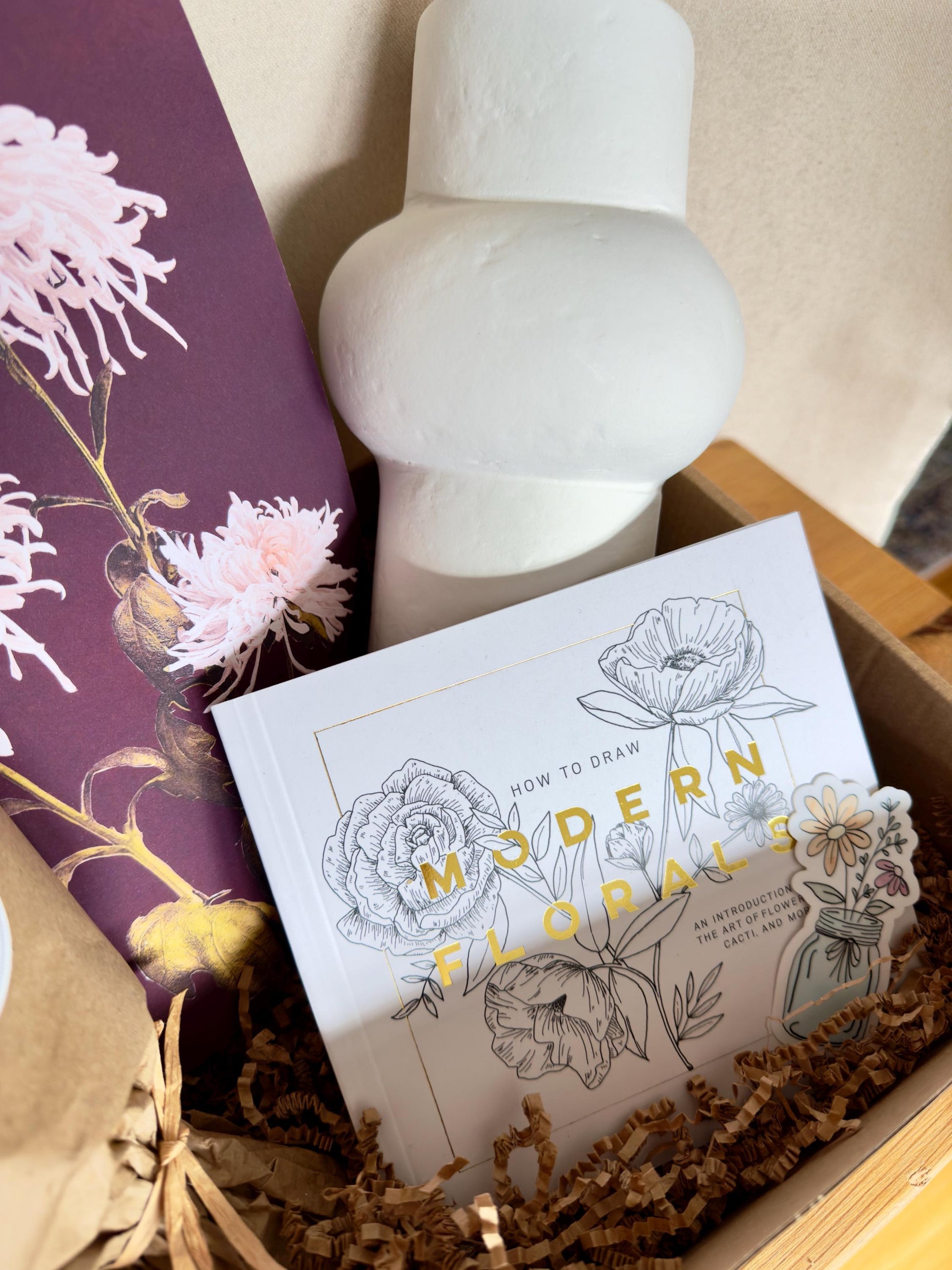Gift box that includes a dried bouquet by Vera Studio, paper mache vase, modern flowers drawing book, print by Ogawa Kazumasa and flower bouquet sticker by Artist Megan Morole.