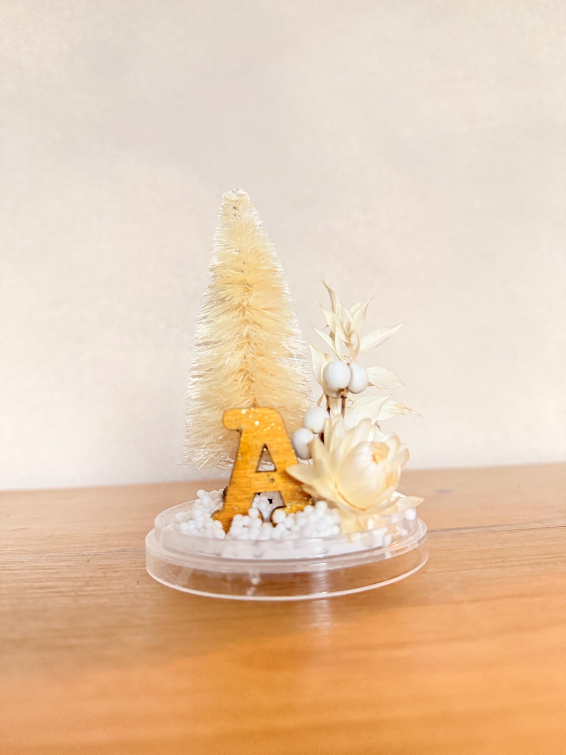 Personalized with initial Ornament - Preserved eucalyptus, dried tallow berries and strawflower, bottlebrush tree and a ochre and sparkle wooden letter on a snow base; hung by a gold color velvet ribbon.